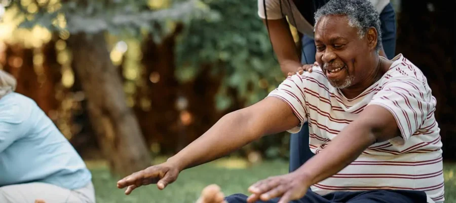 Happy-black-physical-therapist-assists-seniors-during-exercise-class-in-park-1374x1190-1